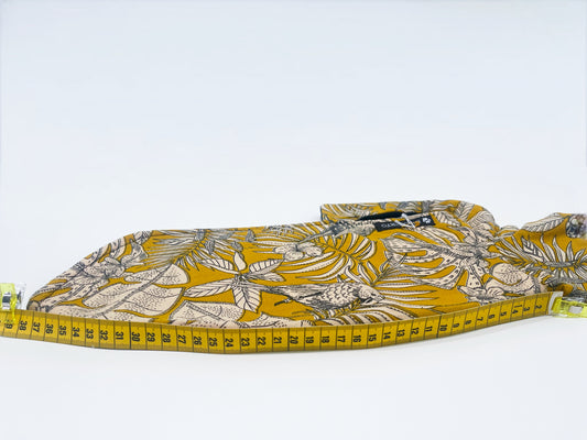 Manteau moutarde à motifs de perroquets INnOVERTO Dog, photographié à plat avec un mètre indiquant la longueur du dos.